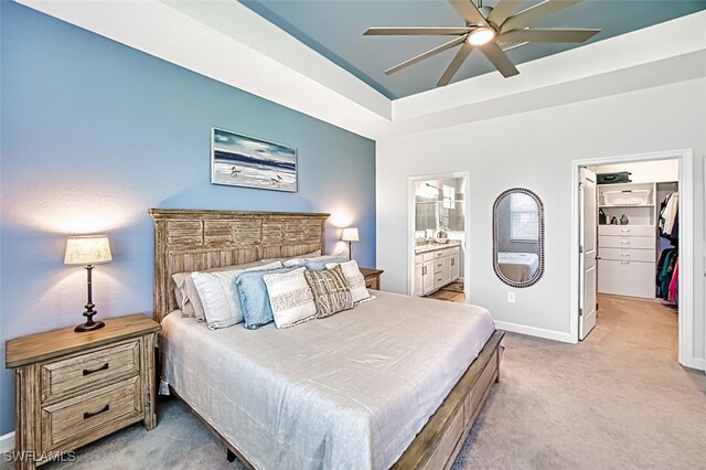 bedroom with a closet, light carpet, ceiling fan, a walk in closet, and ensuite bathroom