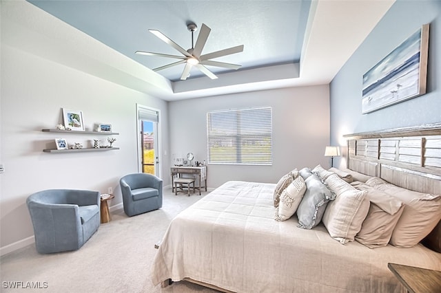 bedroom with light carpet, ceiling fan, and a tray ceiling