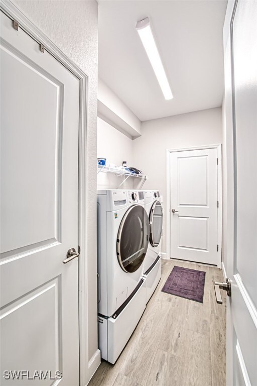 laundry area with washing machine and dryer and light hardwood / wood-style floors