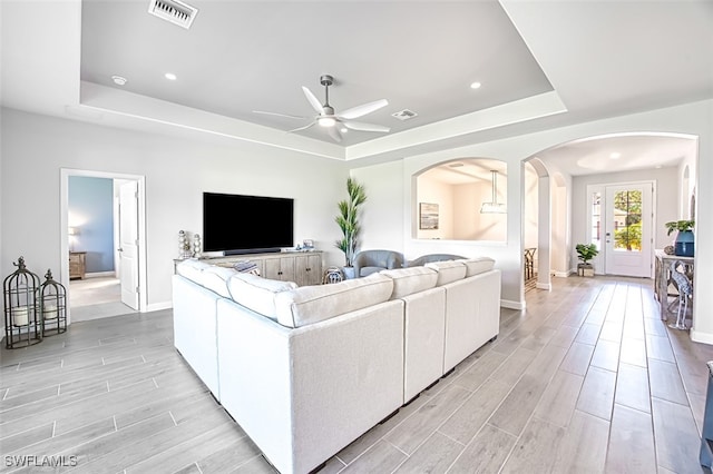 living room featuring ceiling fan and a raised ceiling