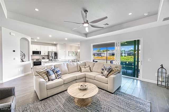 living room featuring ceiling fan and a tray ceiling