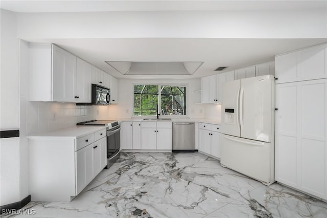 kitchen featuring a tray ceiling, stainless steel appliances, backsplash, sink, and white cabinetry