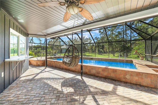 view of swimming pool with a hot tub, glass enclosure, a patio area, and ceiling fan