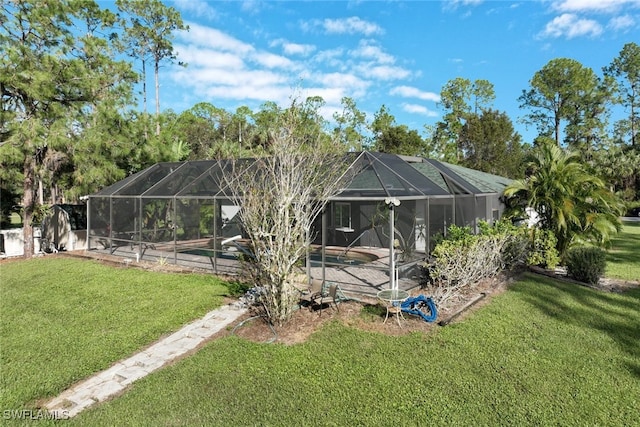 rear view of house with a lawn, a pool, and glass enclosure