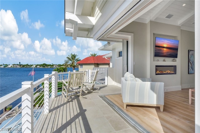 view of patio featuring exterior fireplace and a water view