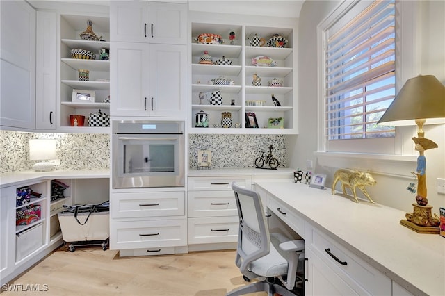 office space with built in desk and light hardwood / wood-style floors