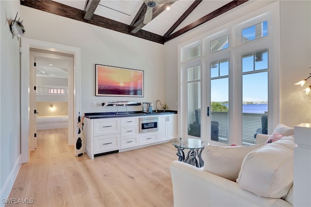 living room featuring beam ceiling, plenty of natural light, light wood-type flooring, wood ceiling, and a ceiling fan
