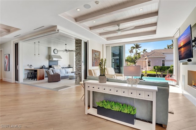 living area with a ceiling fan, light wood-style floors, beam ceiling, a tray ceiling, and wood ceiling