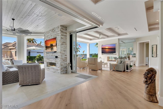 living room featuring a stone fireplace, wood finished floors, and a ceiling fan