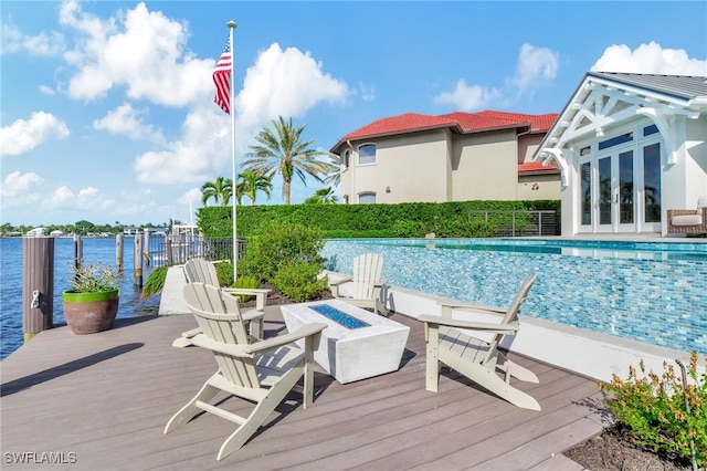 view of swimming pool with an outdoor fire pit and a deck with water view