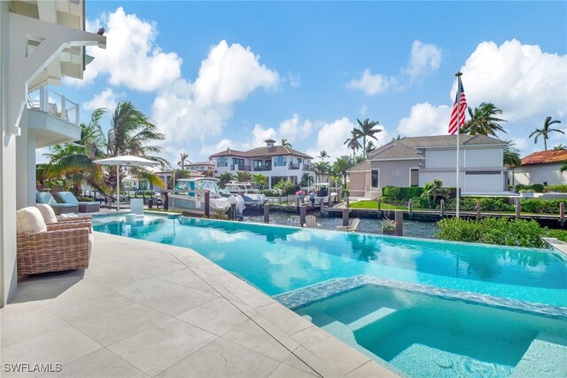 view of pool featuring a water view, an in ground hot tub, and a patio