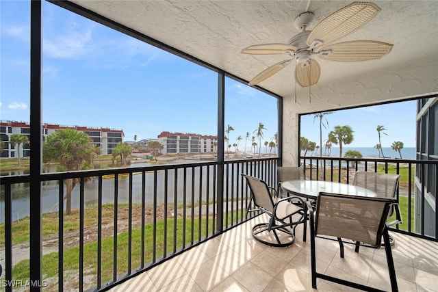 sunroom / solarium featuring a water view and ceiling fan