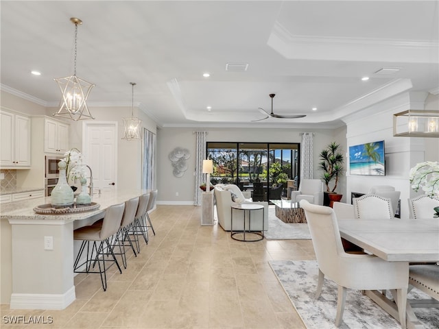 tiled dining area with crown molding, a tray ceiling, and ceiling fan