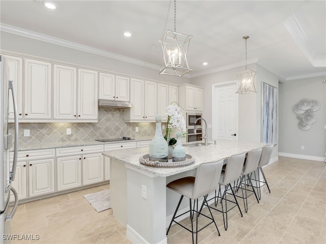 kitchen with a kitchen island with sink, hanging light fixtures, and white cabinets