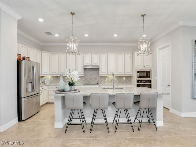 kitchen with light stone countertops, an island with sink, stainless steel appliances, and white cabinetry