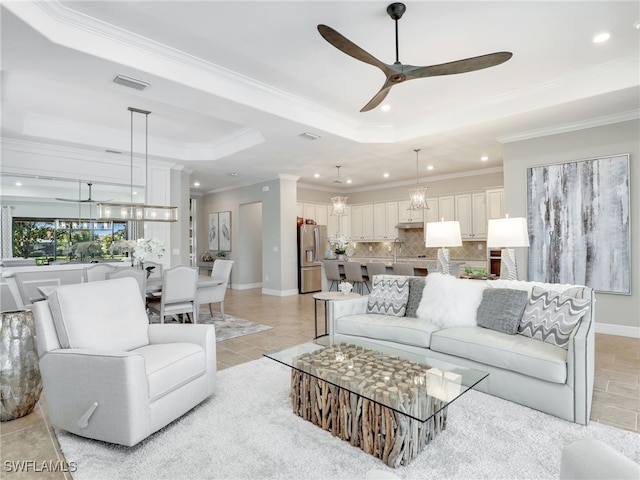 living room with crown molding, a tray ceiling, light tile patterned floors, and ceiling fan