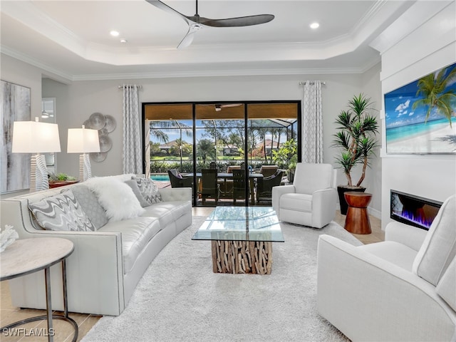 living room with ornamental molding, ceiling fan, and a raised ceiling