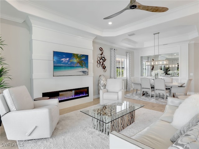 living room featuring ceiling fan, a raised ceiling, ornamental molding, and a fireplace