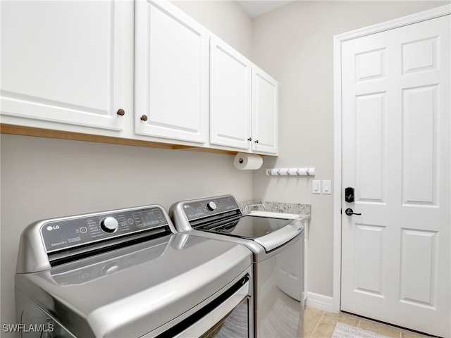 clothes washing area featuring cabinets, washer and dryer, and light tile patterned floors