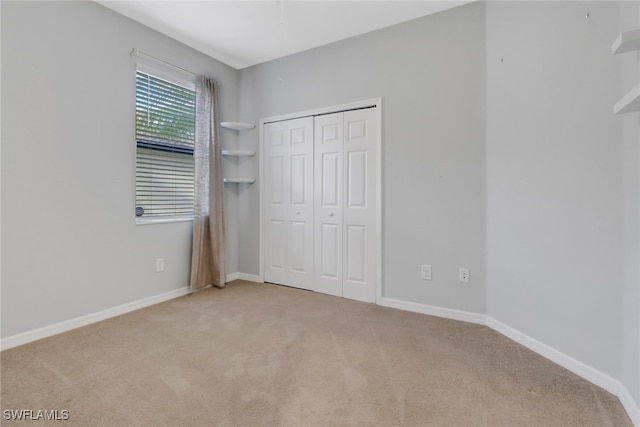 unfurnished bedroom featuring light carpet and a closet