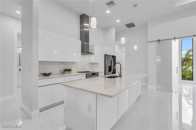 kitchen featuring white cabinetry, stainless steel appliances, decorative light fixtures, and a barn door