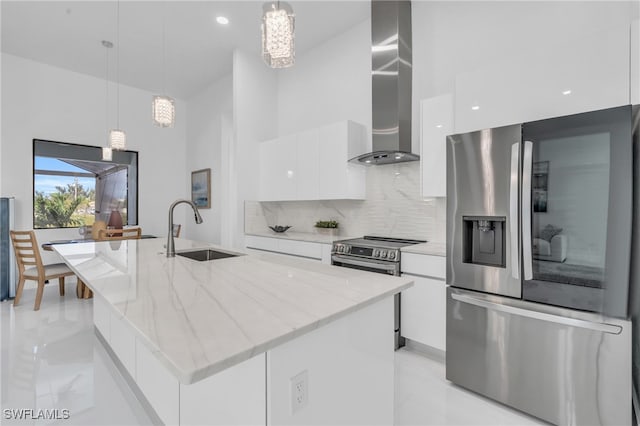 kitchen featuring appliances with stainless steel finishes, white cabinetry, a kitchen island with sink, and decorative light fixtures