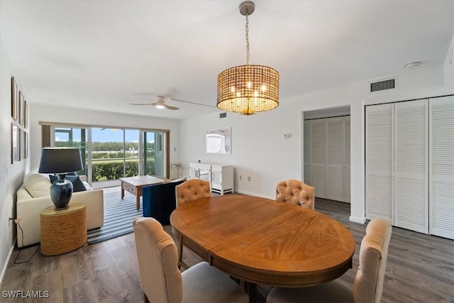 dining area with ceiling fan with notable chandelier and dark hardwood / wood-style floors