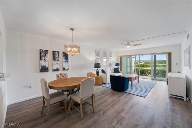 dining area featuring dark hardwood / wood-style flooring and ceiling fan with notable chandelier