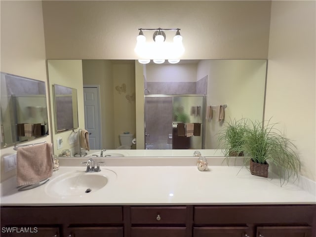 bathroom featuring vanity, toilet, and a shower with door