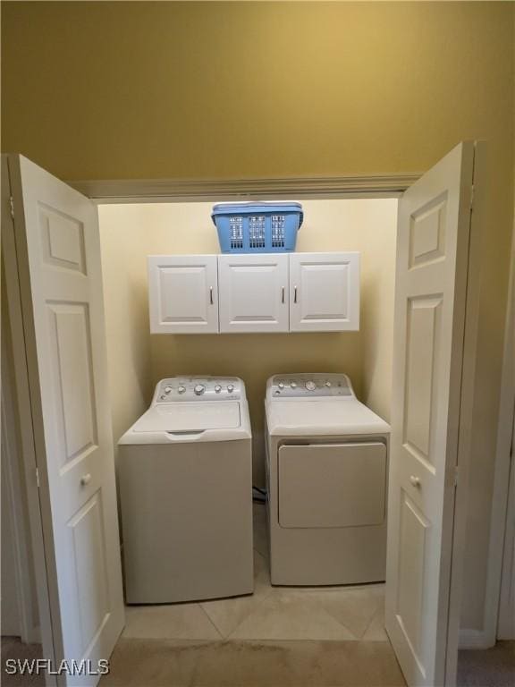 washroom featuring cabinets, light tile patterned flooring, and washer and clothes dryer