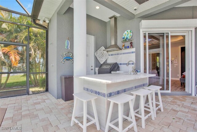 view of patio featuring a lanai, a wet bar, and grilling area