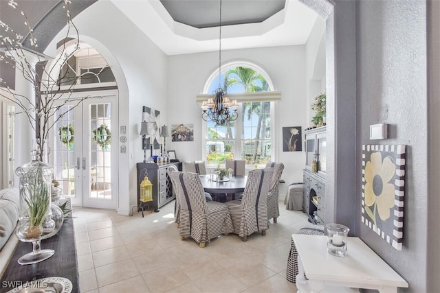 dining area featuring french doors, plenty of natural light, a chandelier, and a raised ceiling