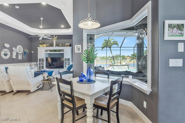 dining space featuring a raised ceiling and ceiling fan