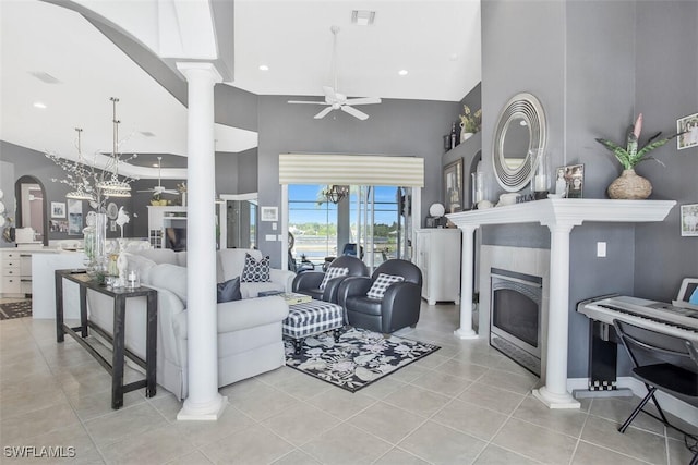 living room featuring light tile patterned floors, a towering ceiling, ceiling fan, and ornate columns