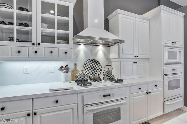 kitchen featuring ventilation hood, tasteful backsplash, white cabinets, and white appliances