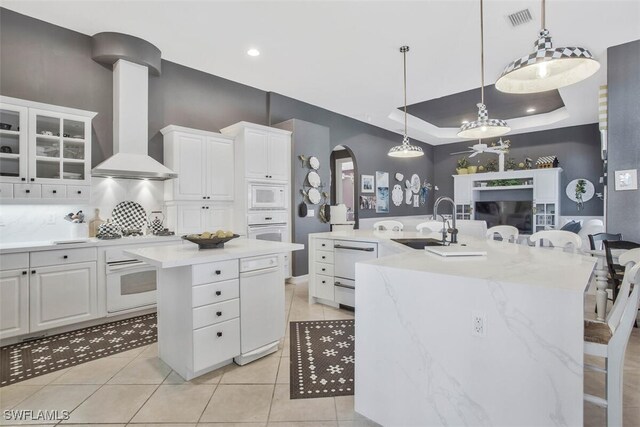 kitchen featuring white cabinetry, white appliances, a breakfast bar, and a center island with sink