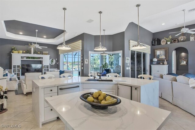 kitchen featuring a kitchen island with sink, white cabinets, ceiling fan, and decorative light fixtures