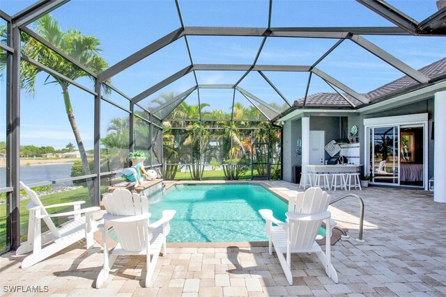 view of pool with exterior bar, glass enclosure, and a patio area