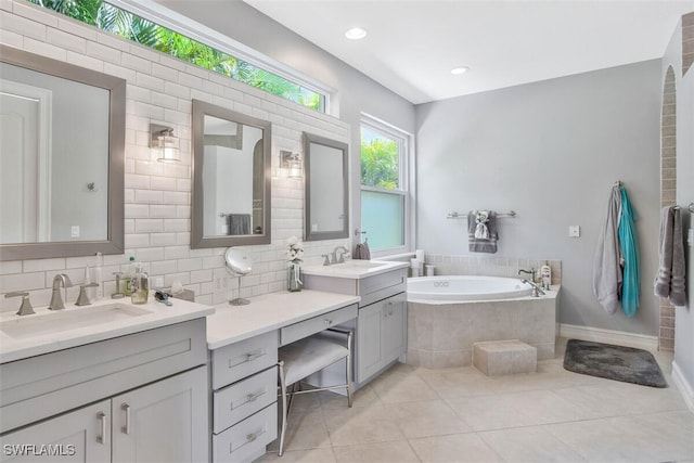 bathroom with tasteful backsplash, vanity, a relaxing tiled tub, and tile patterned floors