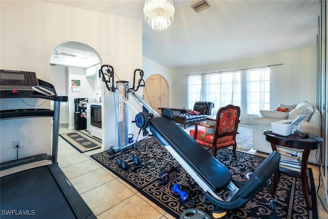 exercise room featuring a notable chandelier and light tile patterned flooring