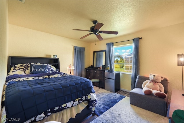 bedroom featuring ceiling fan, a textured ceiling, and fridge