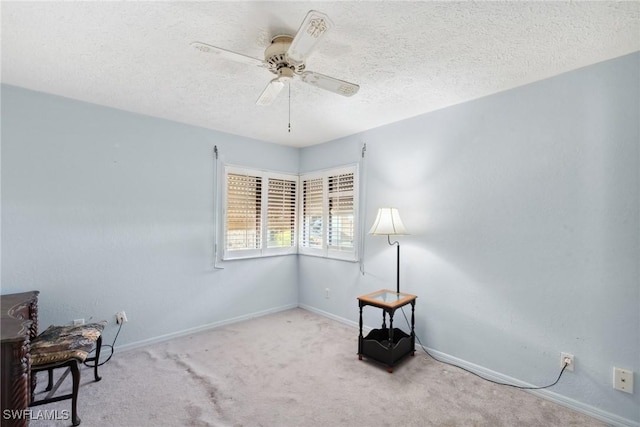 living area with light carpet, ceiling fan, and a textured ceiling