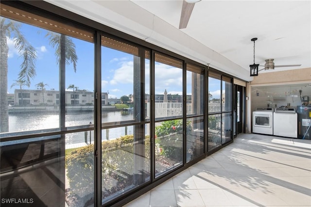 unfurnished sunroom featuring a water view, separate washer and dryer, and water heater