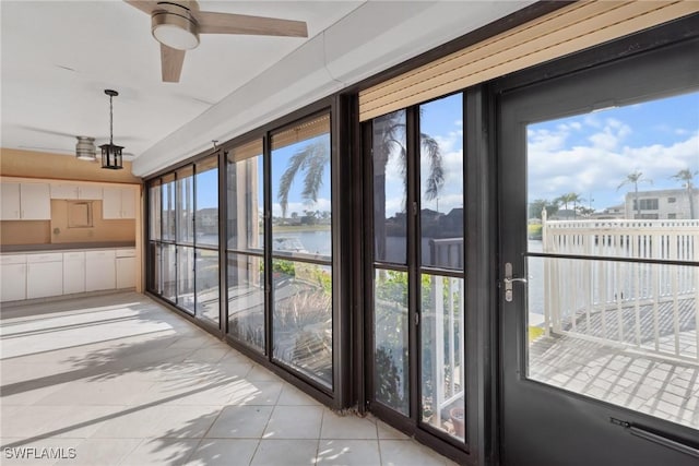 sunroom / solarium featuring a water view, ceiling fan, and a healthy amount of sunlight