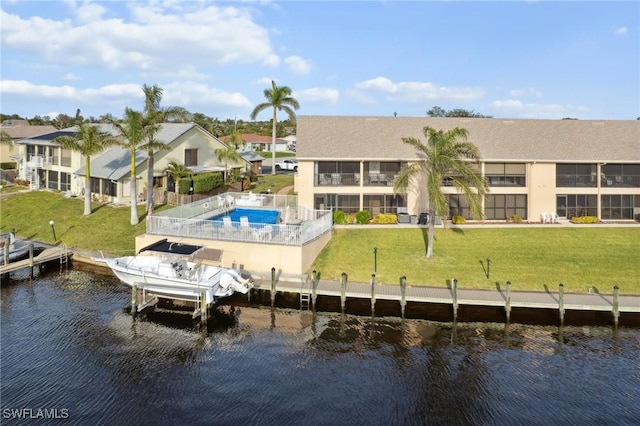 back of house featuring a water view, a yard, and a fenced in pool