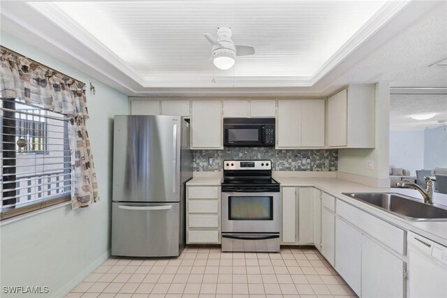 kitchen with sink, ceiling fan, appliances with stainless steel finishes, white cabinetry, and a raised ceiling