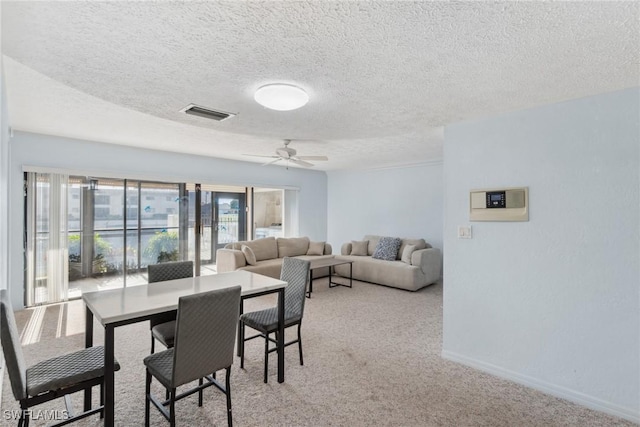 carpeted dining space with a textured ceiling and ceiling fan