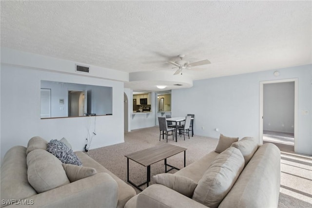 carpeted living room with a textured ceiling and ceiling fan