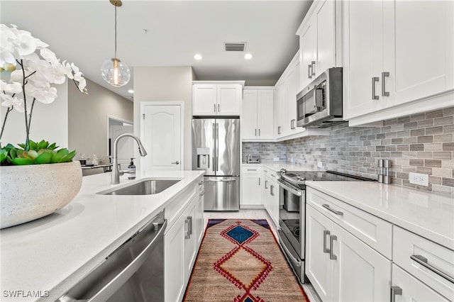 kitchen featuring sink, appliances with stainless steel finishes, decorative backsplash, and white cabinetry