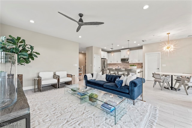 living room featuring light hardwood / wood-style floors and ceiling fan with notable chandelier